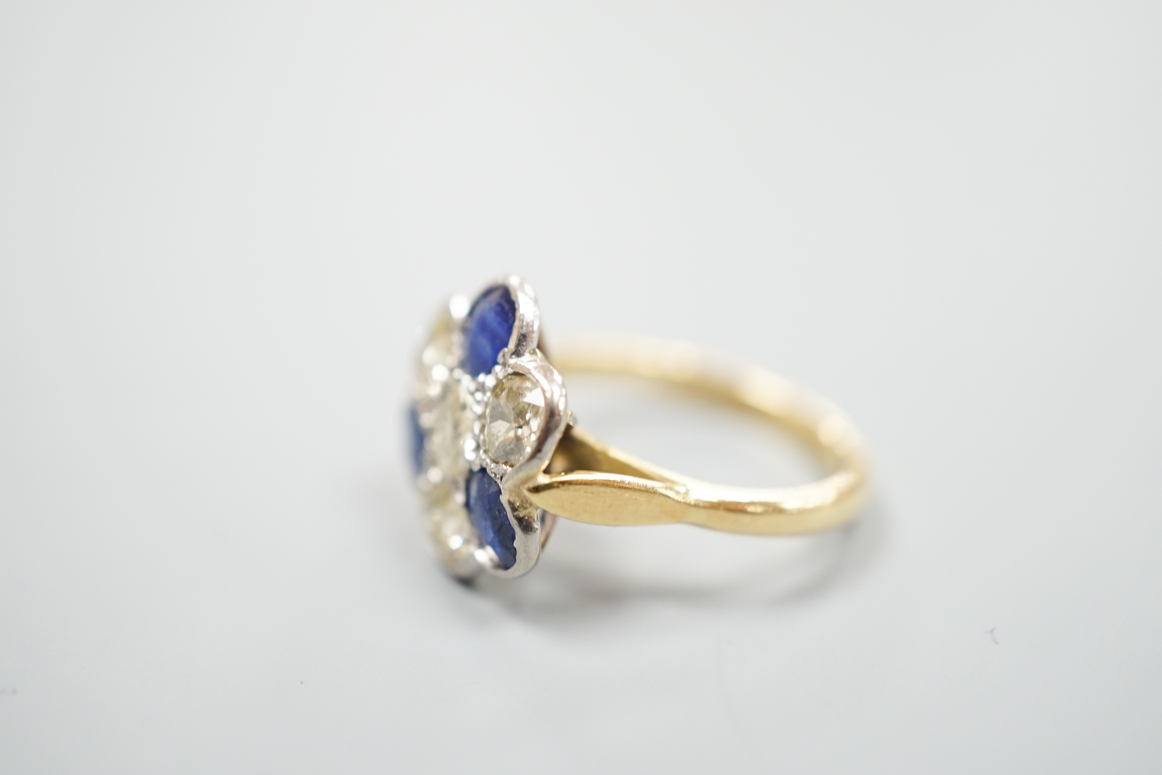 A modern 18ct gold, four stone diamond and three stone sapphire set flower head cluster ring, size J, gross weight 4.1 grams.